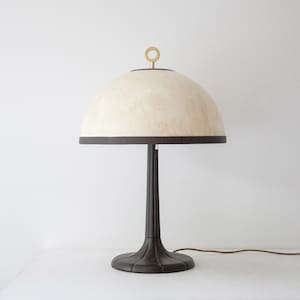 May include: A brown table lamp with a white dome-shaped shade and a gold ring on top. The lamp has a brown cord and a black switch.