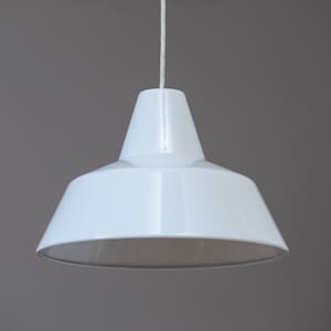 Puede incluir: Una lámpara colgante de metal blanco con una pantalla en forma de cono.