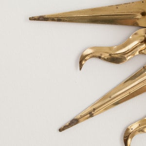 以下が含まれることがあります： 丸い中心と尖った光線を持つ金色のサンバーストミラー。ミラーは金属製で、ヴィンテージスタイルです。