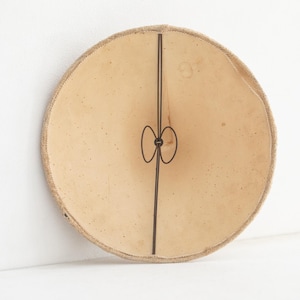May include: A round, beige lampshade with a dark brown metal frame. The lampshade has a textured surface and a decorative metal element in the center. The lampshade is approximately 30 cm in diameter.