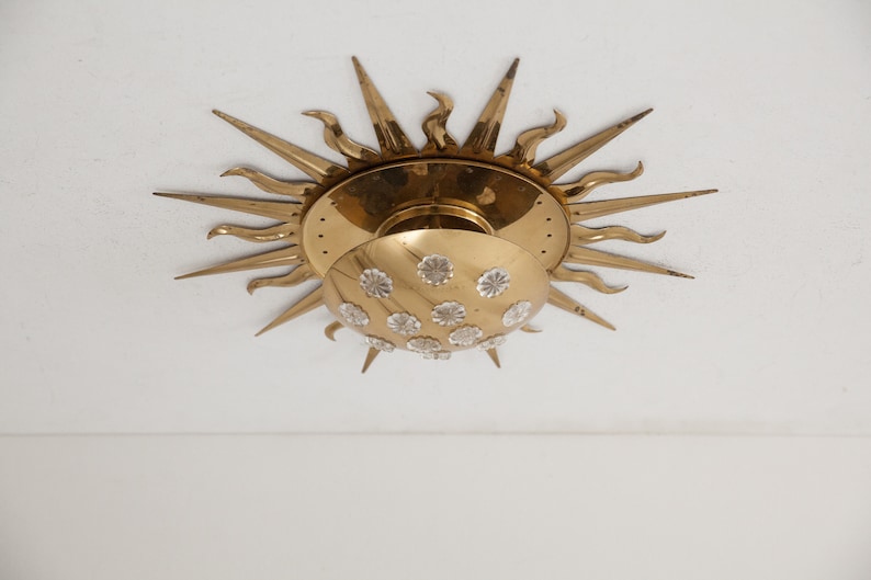 以下が含まれることがあります： クリスタルで覆われた丸いシェードが付いた、金色のサンバースト天井照明器具です。