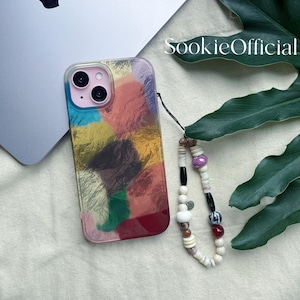 May include: A clear phone case with a colorful abstract design in shades of pink, blue, yellow, and green. The case has a wrist strap with white, black, and colorful beads. The text "SookieOfficial" is visible.