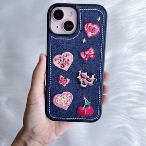 May include: A blue denim iPhone case with embroidered pink hearts, cherries, bows, and the text "Pretty Girl" and "Only You".