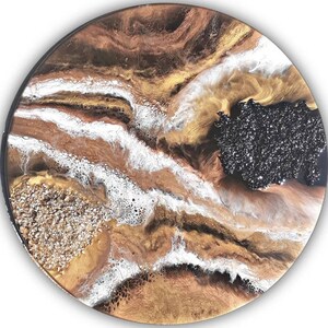 May include: Round abstract art piece with a mix of metallic gold, bronze, and white resin. A section of the artwork features a black, glittery area. The piece has a dark border and a textured appearance.