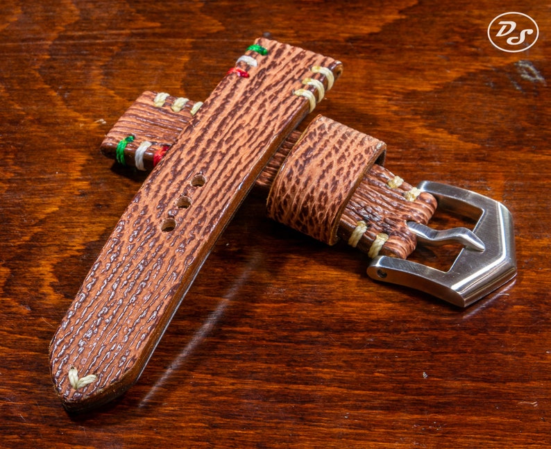 Puede incluir: Una correa de reloj de cuero marr&oacute;n con costuras de colores y una hebilla plateada. La correa tiene una superficie texturizada y est&aacute; dise&ntilde;ada para un reloj de pulsera.