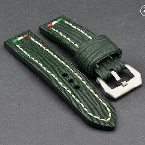 May include: Two green leather watch straps with white stitching and a silver buckle. The straps have a textured surface and a red, white, and green stripe on the top.
