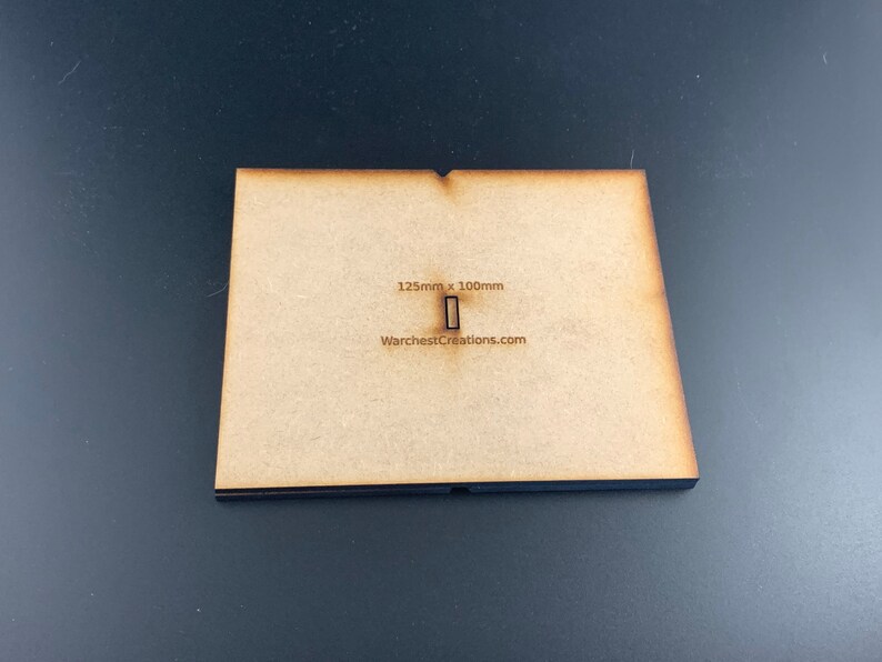 以下が含まれることがあります： 125mm x 100mm の長方形の切り抜きが施された茶色の木製ベース。ベースには「WarchestCreations.com」のラベルが貼られています。