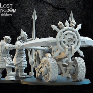 Op de afbeelding: Een grijze plastic miniatuur van een fantasie belegeringswapen met twee figuren die het bedienen. Het wapen heeft een wiel met schedels en spikes, en een lange loop. De figuren dragen armor en houden touwen vast.