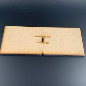 以下が含まれることがあります： 中央に長方形の切り抜きのある薄い茶色の木製ベース。ベースは200mm x 80mmで、「200mm x 80mm」と「watchmakersworkshop.com」の文字が印刷されています。