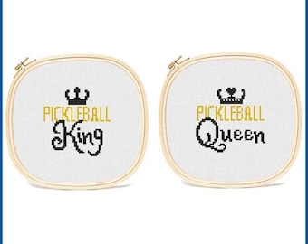 May include: Two wooden embroidery hoops with white fabric stretched across them. The fabric has black text that reads "Pickleball King" and "Pickleball Queen" with a gold crown above each phrase.