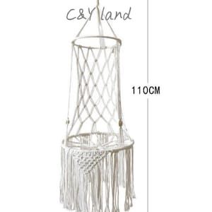 May include: White macrame hanging chair with a fringe bottom. The chair is 40 inches wide and 43.3 inches tall.  C&Yland is written on the top of the chair.