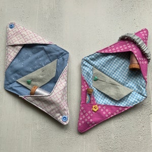 May include: Two fabric needlepoint cases with different patterns. One is blue and white with a white and gray felt insert. The other is pink and white with a blue and white gingham insert. Both cases have a small spool of thread and a pin inside.