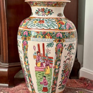 May include: A large ceramic floor vase with a cream-colored base featuring colorful hand-painted scenes of figures in traditional attire, floral motifs, and intricate geometric borders in shades of pink, green, yellow, blue, and orange.