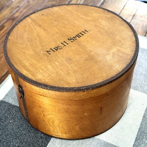 May include: A circular wooden box with a lid, featuring a light brown hue and a darker trim. The lid is inscribed with "MRS. H. SMITH". The box rests on a black and white checkered surface. The box's diameter is approximately 20 cm.