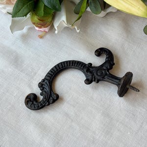 Appendiabiti antico in ghisa: decorazione vittoriana a volute di acanto e serpente, circa 1910.