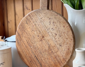 Tabla de pan antigua de madera rústica con forma de pala, estilo granja, con grietas.