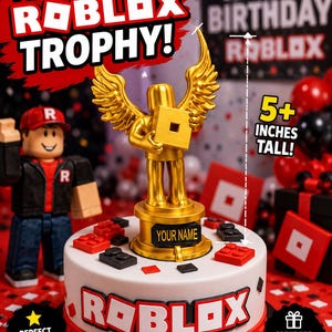 May include: A gold-colored Roblox trophy cake topper featuring a winged figure holding a square logo, standing on a circular base with a nameplate. The trophy is 5+ inches tall and sits on a white cake decorated with red and black blocks and the Roblox logo.