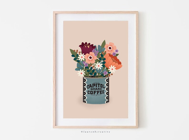 May include: A framed print of a vintage coffee can with a bouquet of flowers in it. The can is blue with white lettering that says "Capitol Brand Coffee". The flowers are red, orange, pink, white, and purple.