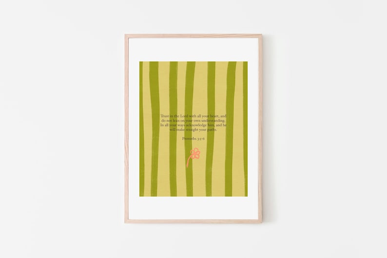 May include: A framed print with a light wood frame. The artwork features a background of vertical green stripes. Text in the center reads "Trust in the Lord with all your heart..." with a small pink flower below. Proverbs 3:5-6.