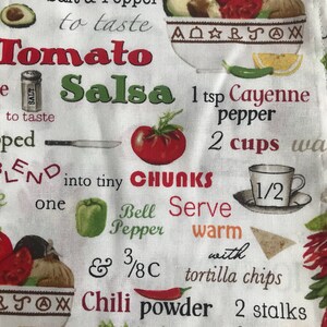 May include: A white kitchen towel with a red and green tomato salsa recipe printed on it. The recipe includes ingredients like chopped tomatoes, bell pepper, celery, and chilli powder. The text also includes instructions to blend the ingredients into tiny chunks and serve warm with tortilla chips.