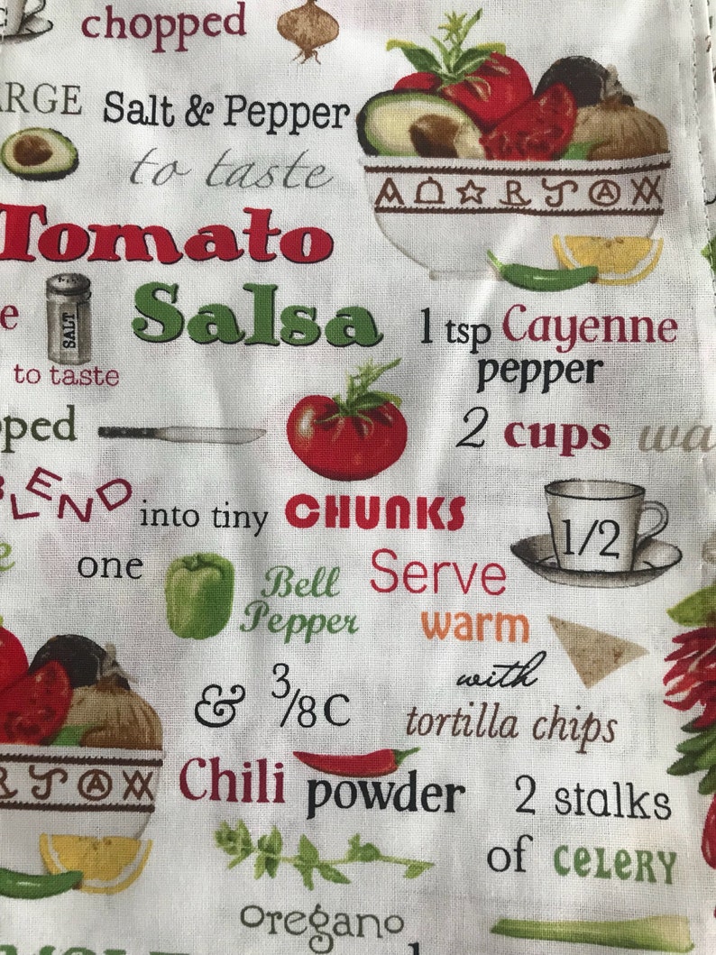 May include: A white kitchen towel with a red and green tomato salsa recipe printed on it. The recipe includes ingredients like chopped tomatoes, bell pepper, celery, and chilli powder. The text also includes instructions to blend the ingredients into tiny chunks and serve warm with tortilla chips.