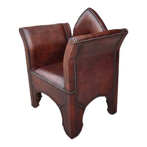 May include: A brown leather chair with a distinctive, pointed back and studded details. The chair has a simple, square seat and four legs.