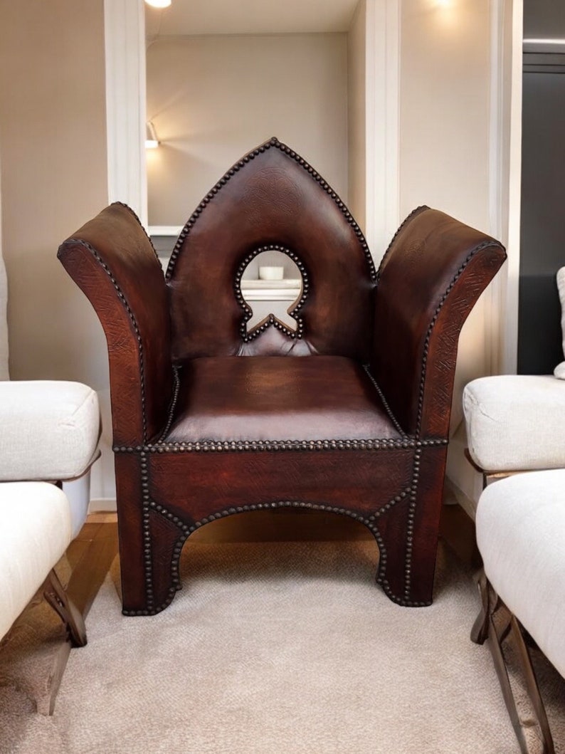 May include: A brown leather armchair with a distinctive arched back and studded detailing. The chair features a cutout in the back and is positioned on a light beige rug.