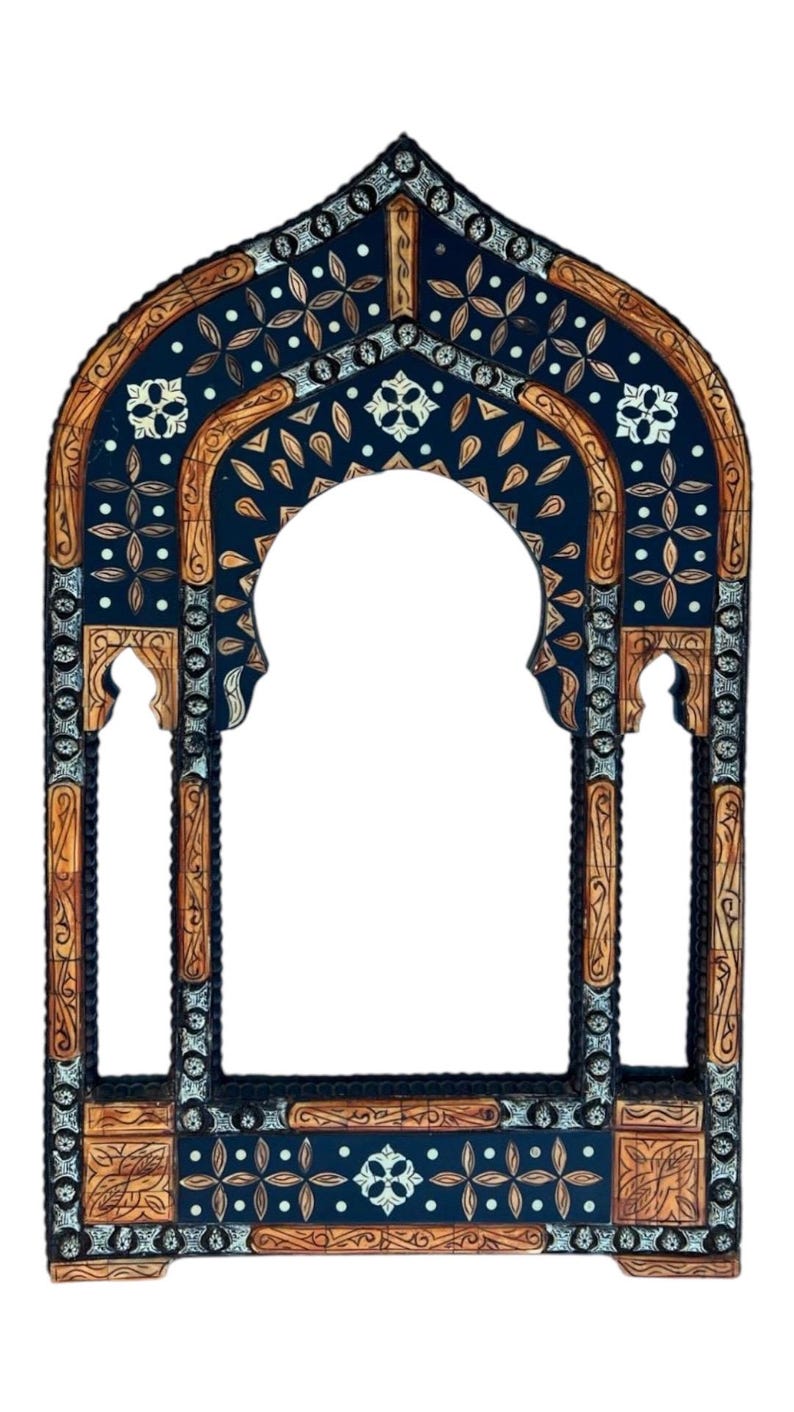 May include: An arched wall mirror frame featuring intricate inlay work with dark blue and light brown wood panels. The design includes repeating floral motifs, geometric patterns, and small white circular accents throughout the structure.