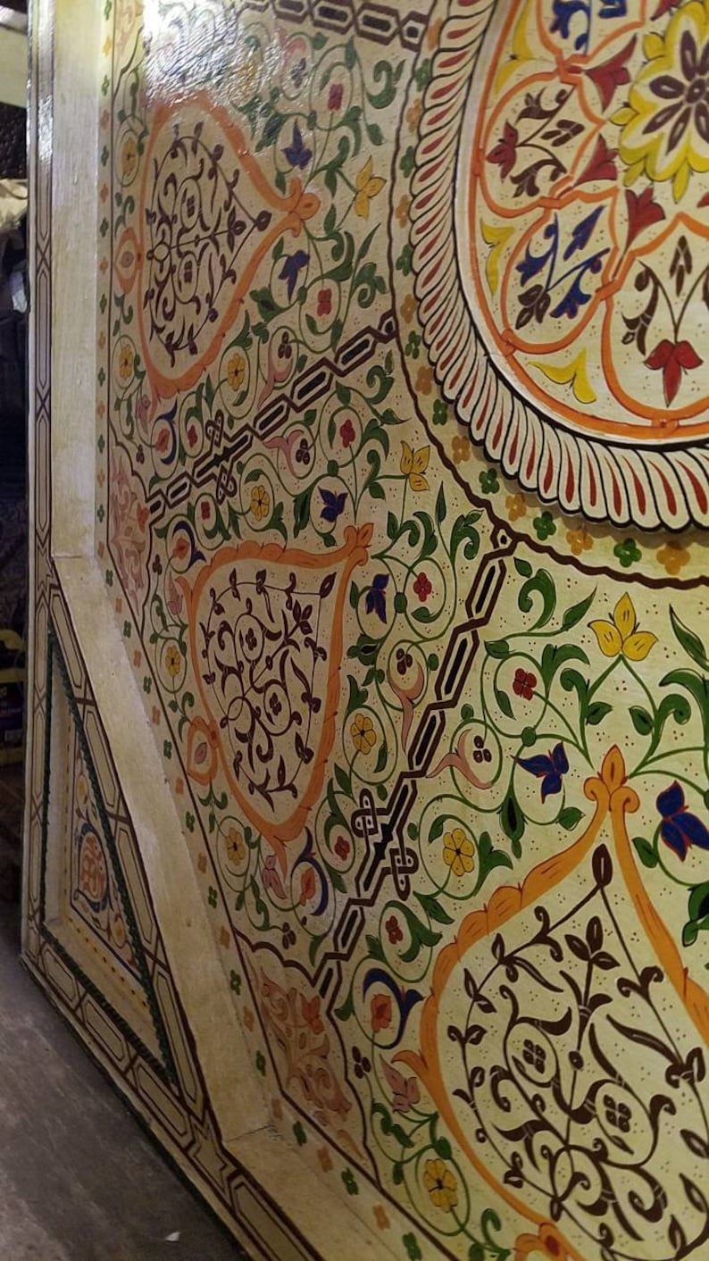 K&ouml;nnte beinhalten: Nahaufnahme einer Decke, die mit komplizierten floralen Mustern in Gelb-, Orange-, Gr&uuml;n-, Blau- und Rott&ouml;nen bemalt ist. Das Design zeigt stilisierte Bl&auml;tter, Blumen und geometrische Formen.