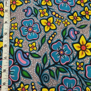 May include: Fabric with a floral pattern featuring large teal and yellow flowers with pink and purple accents on a gray background. The design includes green leaves and stems, with a dotted texture.