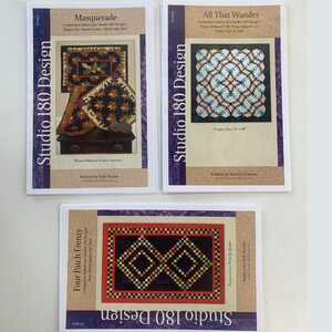 Peut inclure: Trois livres de modèles de courtepointe de Studio 180 Design. Les couvertures présentent des motifs de courtepointe colorés avec les titres "Masquerade", "All That Wander" et "Four Patch Frenzy".