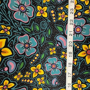 May include: A fabric with a floral pattern featuring large turquoise, yellow, and pink flowers on a black background. Green leaves and small yellow flowers are also present. A ruler shows the fabric's dimensions.