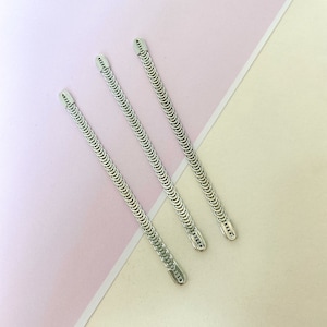 Puede incluir: Tres pinzas para el pelo de cadena de plata con acabado plateado. Las pinzas están dispuestas en fila, con la pinza superior ligeramente desplazada hacia la derecha.