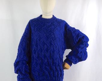 May include: A royal blue knitted sweater with a cable knit pattern. The sweater has a crew neck and long sleeves.
