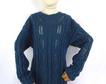 May include: A teal blue knitted jumper with a crew neck and long sleeves. The jumper features a textured, open-weave design with vertical and horizontal patterns. The garment is displayed on a mannequin against a white background.