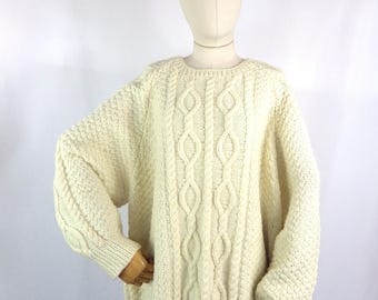 May include: A cream-colored cable knit sweater with a loose fit and long sleeves.