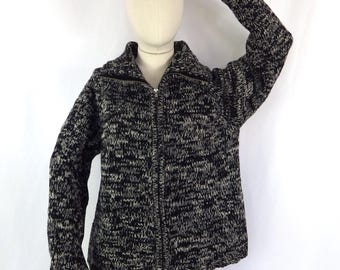 May include: Black and white knitted cardigan with a zip fastening. The cardigan has a textured knit pattern and a relaxed fit.