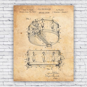 May include: A vintage black and white line drawing of a snare drum patent. The patent is titled "Snare Drum" and was filed on January 16, 1962, by J.B. Thompson. The patent number is 3,113,481.