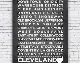 May include: Black and white typography print of Cleveland neighborhoods on a chalkboard background. The text includes "Downtown Ohio City", "Warehouse District", "Cleveland Heights", "University Circle", "Detroit Shoreway", "Old Brooklyn Jefferson", "Gordon Square", "Shaker Heights Tremont", "West Boulevard", "East 4th St Collinwood", "Slavic Village Edgewater", "East Cleveland The Flats", "Little Italy Stockyards", "Coventry Lakewood", "University Heights", and "Cleveland".