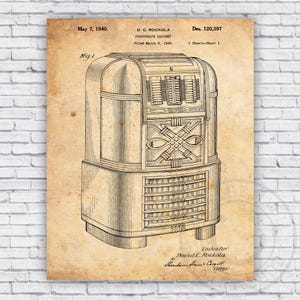 May include: Vintage patent print of a D.C. Rockola phonograph cabinet, dated May 7, 1940. The black and white illustration shows the front of the jukebox with detailed mechanical elements and text. The print is on a tan background.