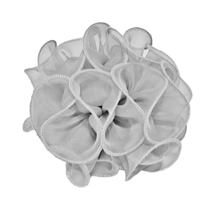 May include: A light gray, ruffled fabric flower, possibly a hair accessory or decorative element. The flower has multiple layers of soft, sheer fabric with a delicate, stitched edge. The overall shape is round and full, with a slightly textured appearance.