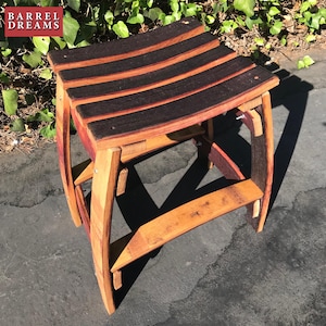 May include: A wooden stool made from repurposed wine barrels. The seat is made of dark wood slats and the legs are made of light wood. The stool is sitting on a gray concrete surface.