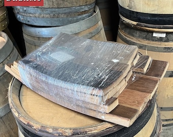 May include: A stack of wooden barrel staves wrapped in plastic. The staves are a light brown color with darker brown streaks. The staves are stacked on top of a wooden barrel.