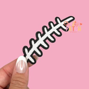 May include: A black and white embroidered patch in a leaf design. The patch has a black outline and a white interior. The patch is held against a pink background. The text "Crafty Patch Studio" is visible in the upper right corner.
