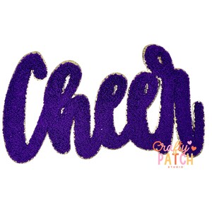 May include: A purple chenille patch with the word "Cheer" in a cursive font. The patch has a gold border and a textured appearance. The "Crafty Patch Studio" logo is in the lower right corner.