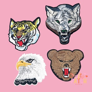 May include: Four embroidered animal patches: a tiger, a wolf, an eagle, and a bear. The tiger has yellow and black stripes, the wolf is gray, the eagle is white with a yellow beak, and the bear is brown. Each patch has a detailed design.