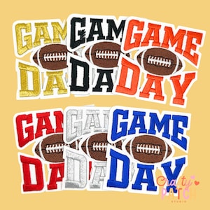 May include: A collection of embroidered patches with the words "GAME DAY" in various colors, including gold, black, orange, red, silver, and blue. Each patch features a brown football. The patches are arranged on a light yellow background.