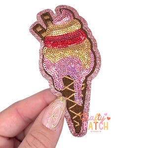 May include: A sequined ice cream cone patch with pink, red, and gold sequins. The cone is brown with a glittery pink border. The patch has the text "Crafty Patch Studio".