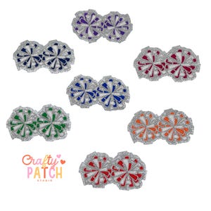 May include: A collection of embroidered pom-pom patches in various colors, including purple, navy, red, green, blue, and orange. Each pom-pom has a silver glitter border. The Crafty Patch Studio logo is visible.