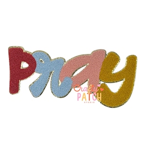 May include: A colorful patch with the word "PRAY" in a stylized font. The letters are textured and in shades of red, blue, pink, and gold. The patch has a gold border and the text "Crafty Patch Studio" is visible.